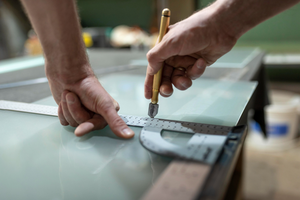 Man using a hand-held glass cutter to score glass. Photo by freepik (Magnific)