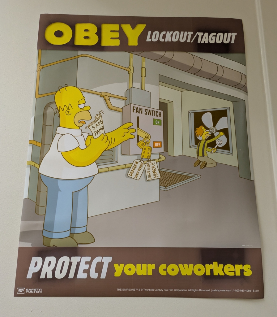 Sign that reads "Obey lockout/tagout – Protect your coworkers." Homer Simpson is reaching for the lockout tags in the panel while a colleague is working on a fan.