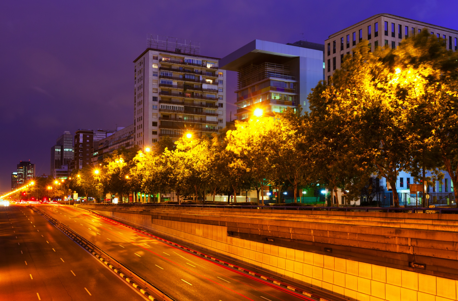 Apartment buildings lit up at night near a highway. Photo by bearfotos (Magnific)