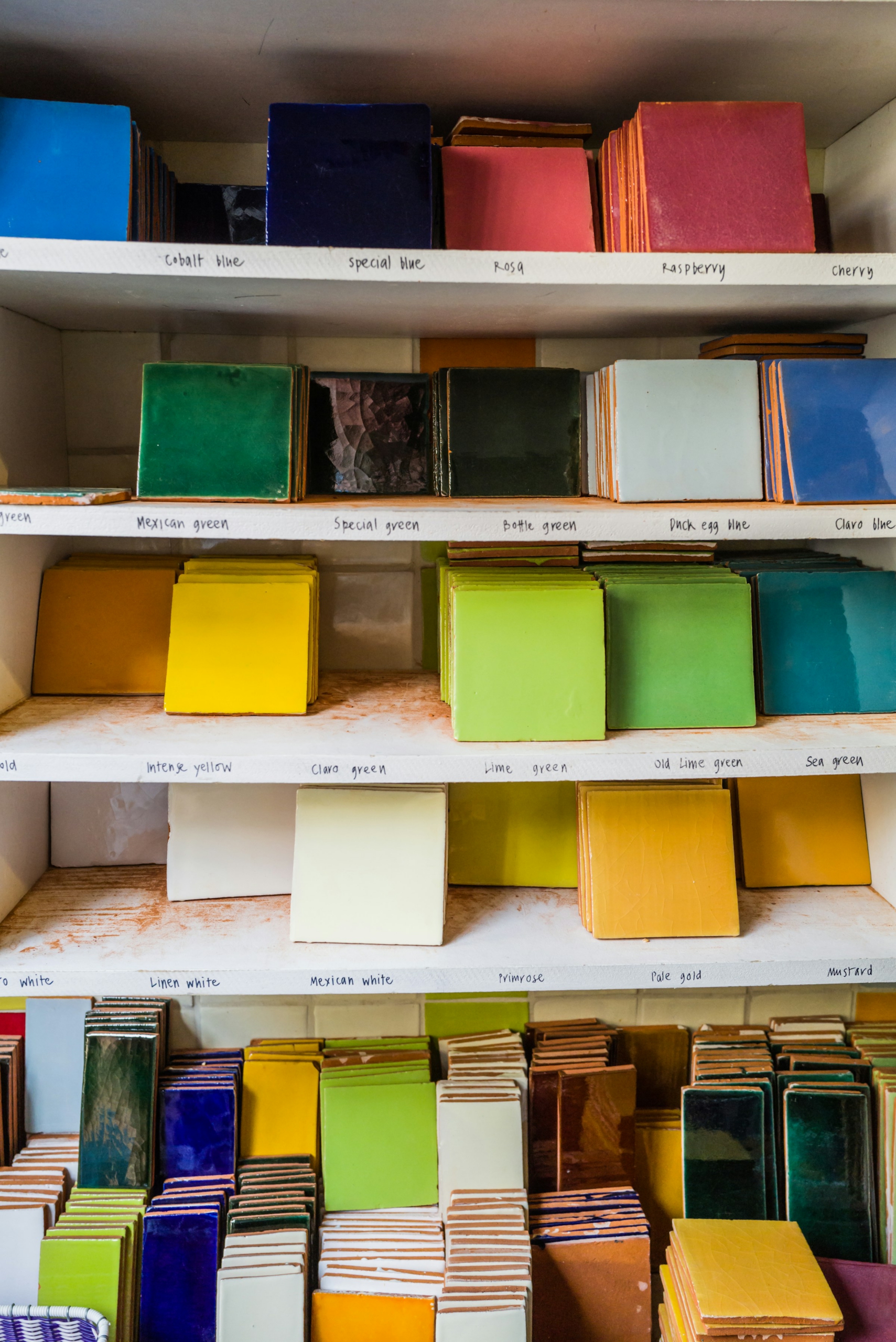 Colourful painted tiles on a shelf. Photo by Georg Eiermann (Unsplash)