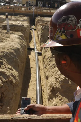 A laser measure used outdoors on a plumbing job