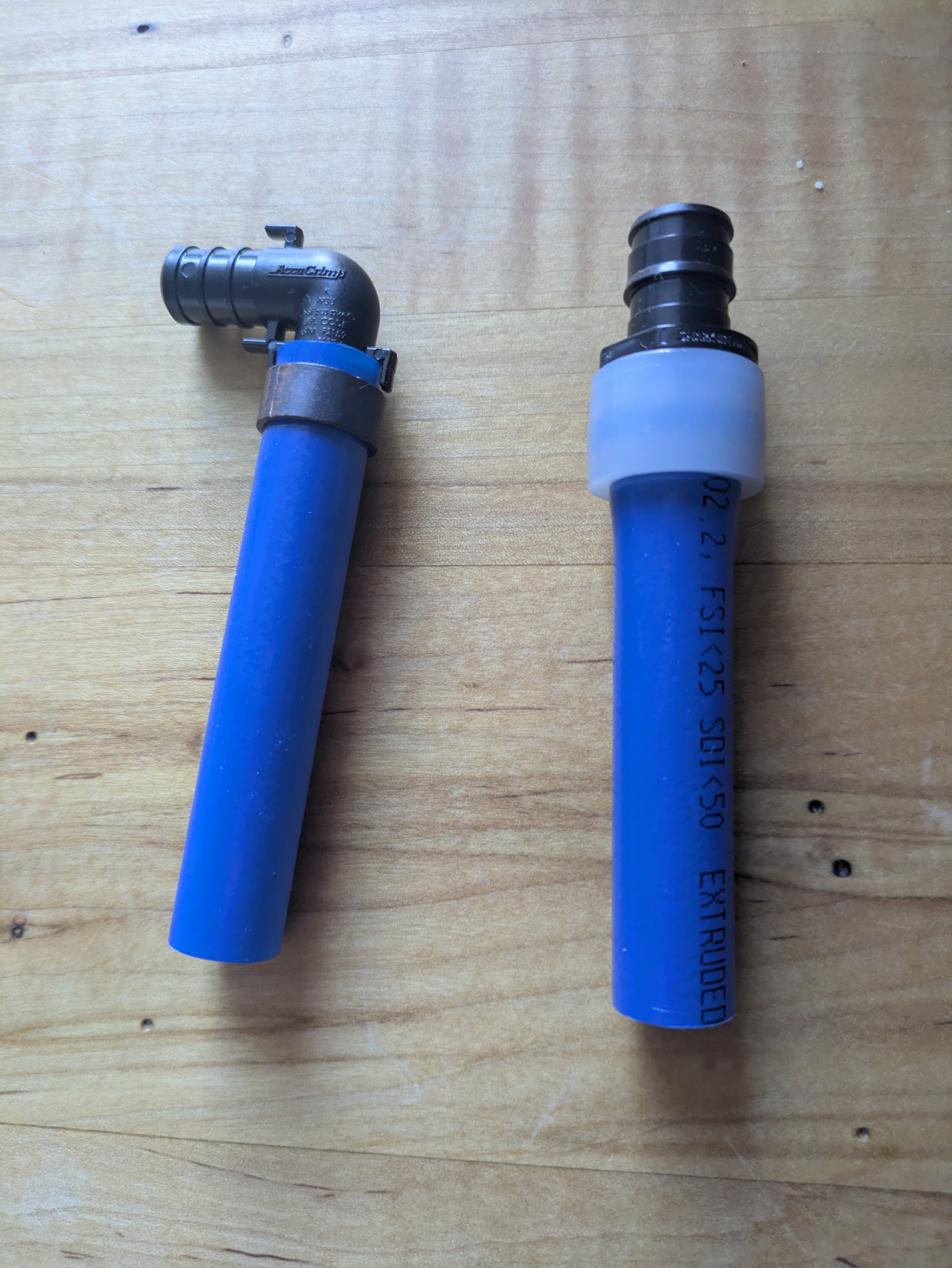 Blue cold water PEX pipe with 2 different types of fittings: crimp (left) and expansion (right)