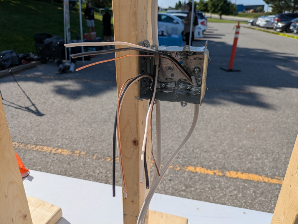 2-gang electrical box with wire fed from the power source above, and out of 2 knockouts below, to the receptacle and to the light fixture
